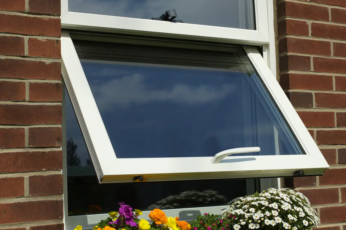 Wit kunststof raam met draaikiepbeslag in een bakstenen gevel met dubbel glas